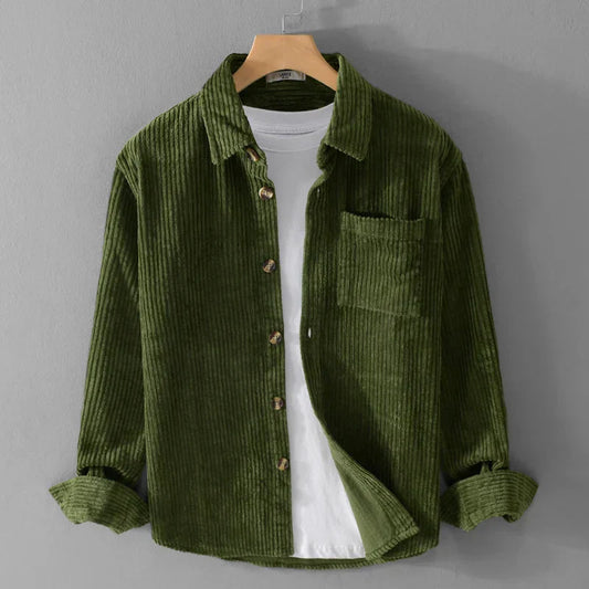 Camicia di velluto a coste verde oliva su gruccia, con tasca frontale e bottoni in legno, sopra una maglietta bianca. Moda uomo casual elegante.