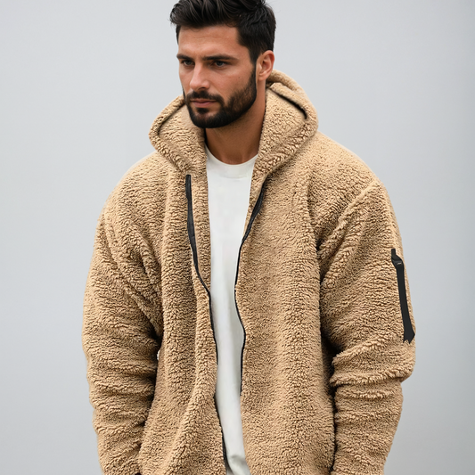 Uomo con giacca in pile beige, cappuccio, zip nera, sfondo grigio. Moda autunnale, abbigliamento casual, stile moderno, comfort caldo.