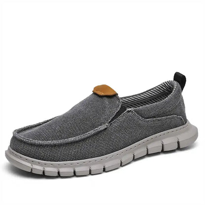 Scarpa casual grigia da uomo, tessuto traspirante, suola in gomma bianca, design slip-on, ideale per comfort quotidiano e stile urbano.
