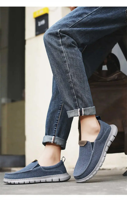Scarpe slip-on casual blu in tessuto, indossate con jeans arrotolati. Calzature comode e moderne per uno stile urbano e rilassato.