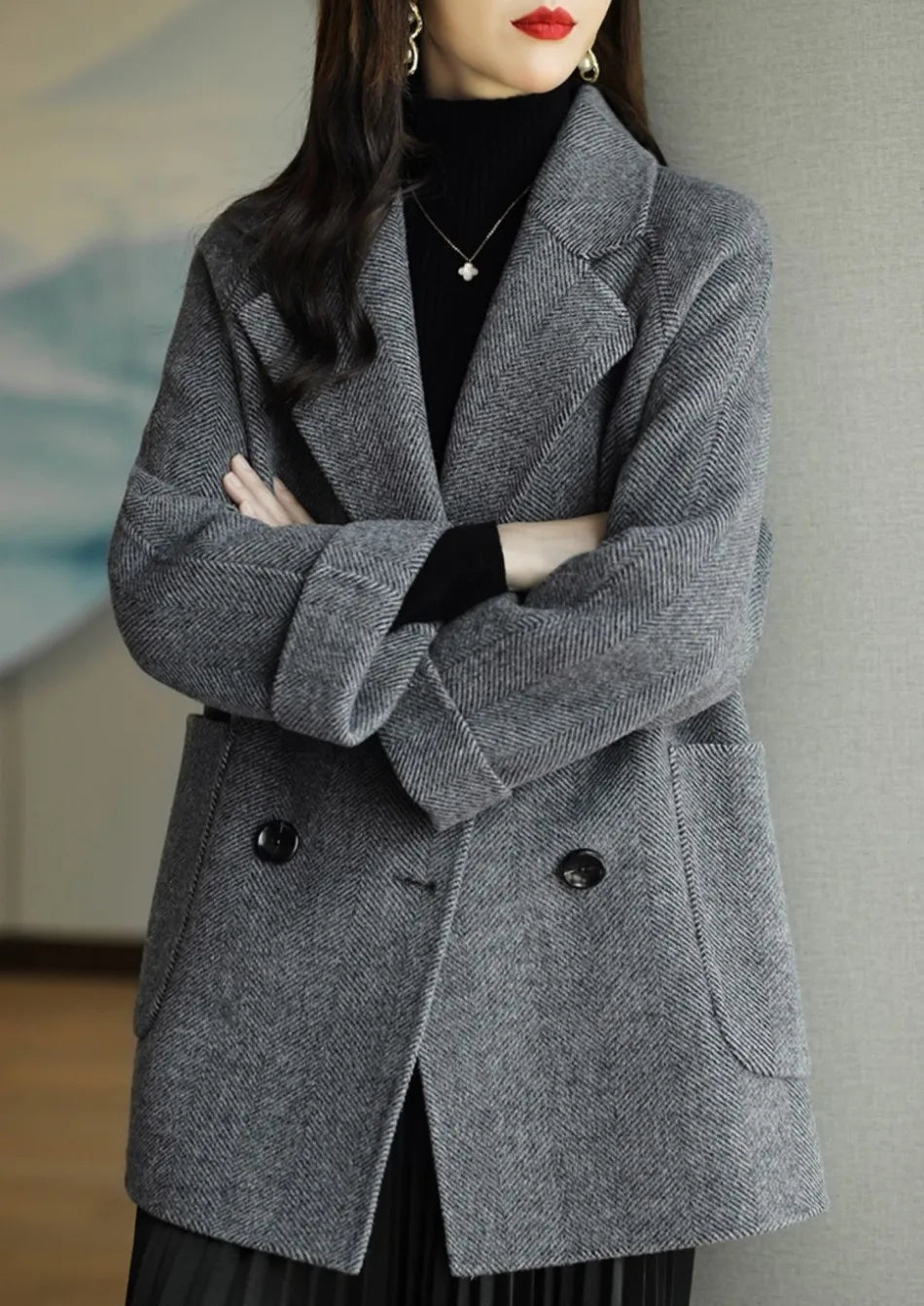 Donna con cappotto grigio elegante, doppio petto, tessuto a spina di pesce, indossa dolcevita nero. Moda autunnale, stile sofisticato.