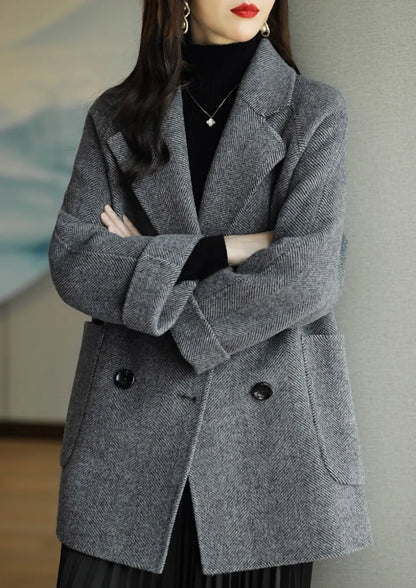 Donna con cappotto grigio elegante, doppio petto, tessuto a spina di pesce, indossa dolcevita nero. Moda autunnale, stile sofisticato.