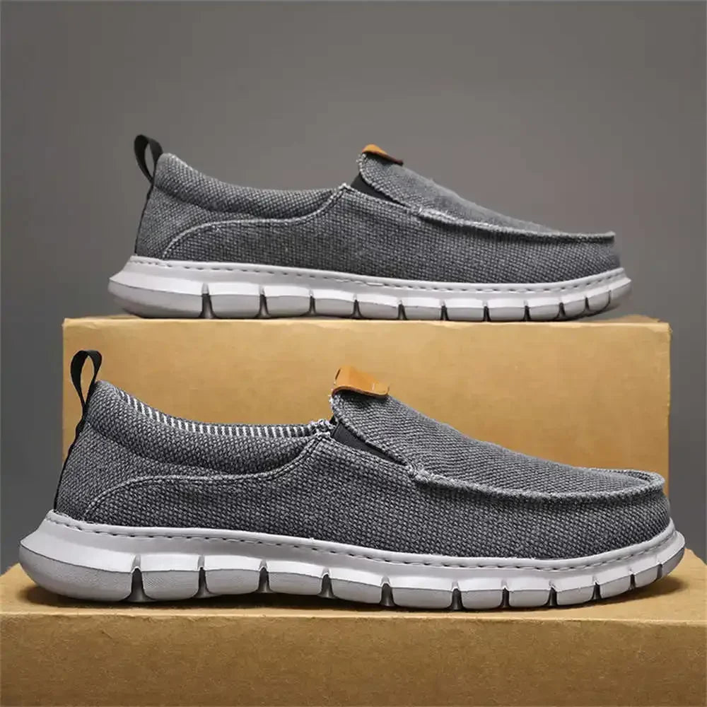 Scarpe slip-on grigie da uomo su scatola di cartone, suola bianca, design casual e traspirante, ideali per passeggiate e tempo libero.