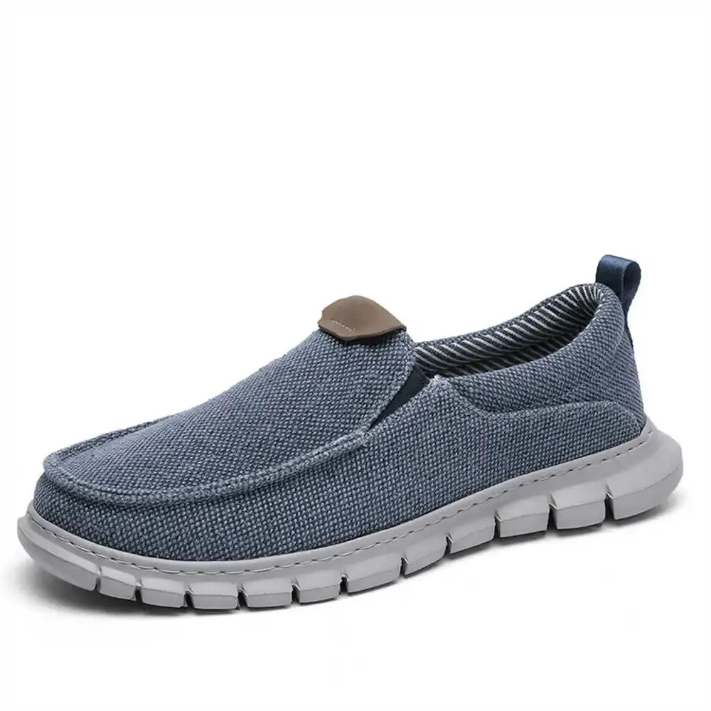 Scarpa slip-on casual da uomo in tessuto blu, suola bianca antiscivolo, design leggero e traspirante, ideale per passeggiate e tempo libero.