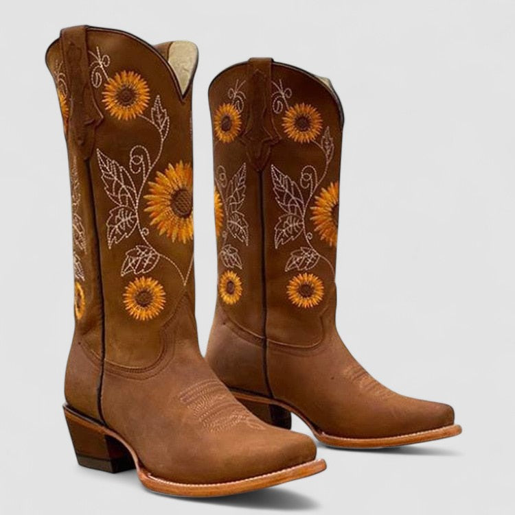 Stivali da cowboy marroni con ricami di girasoli e foglie, tacco basso, punta quadrata. Scarpe western eleganti e artigianali.