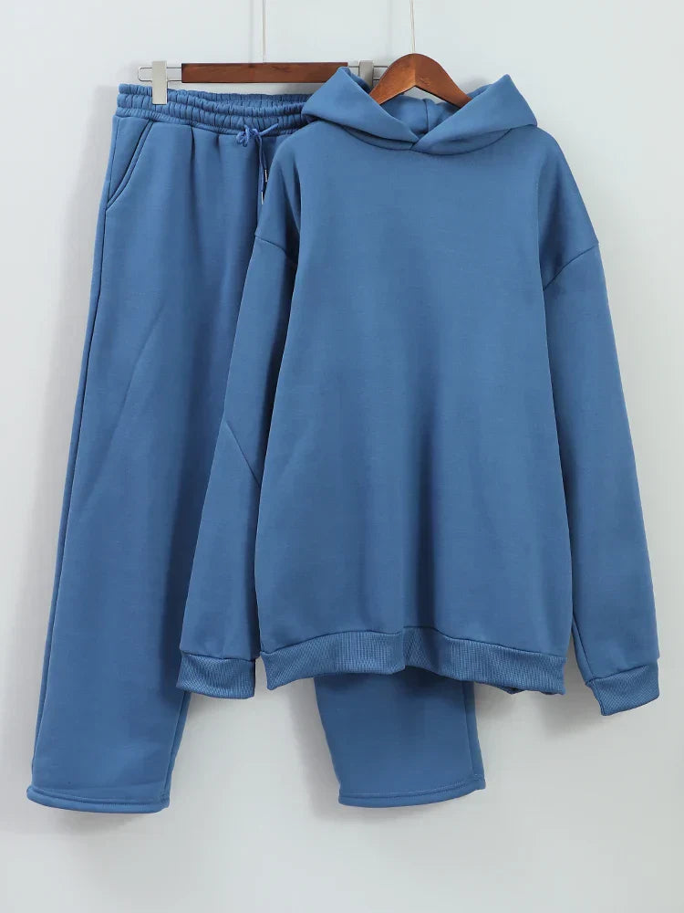 Tuta sportiva blu in cotone, composta da felpa con cappuccio e pantaloni con elastico in vita. Abbigliamento casual e comodo per uomo e donna.