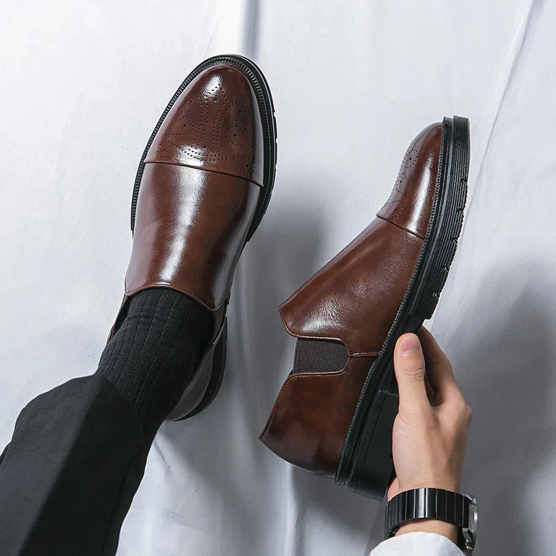 Scarpe eleganti da uomo in pelle marrone, design slip-on, suola nera, indossate con calzini neri e pantaloni scuri. Moda maschile classica.