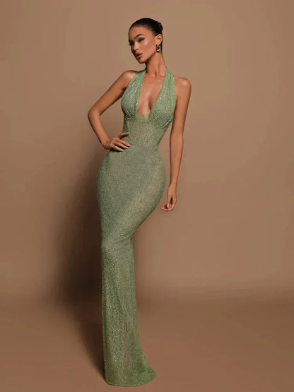 Donna in abito lungo verde scintillante, scollatura profonda, posa elegante su sfondo beige. Moda, eleganza, abito da sera glamour.