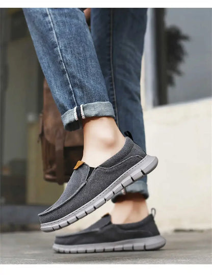 Scarpe casual uomo grigie, suola antiscivolo, indossate con jeans. Calzature comode e traspiranti per passeggiate e tempo libero.