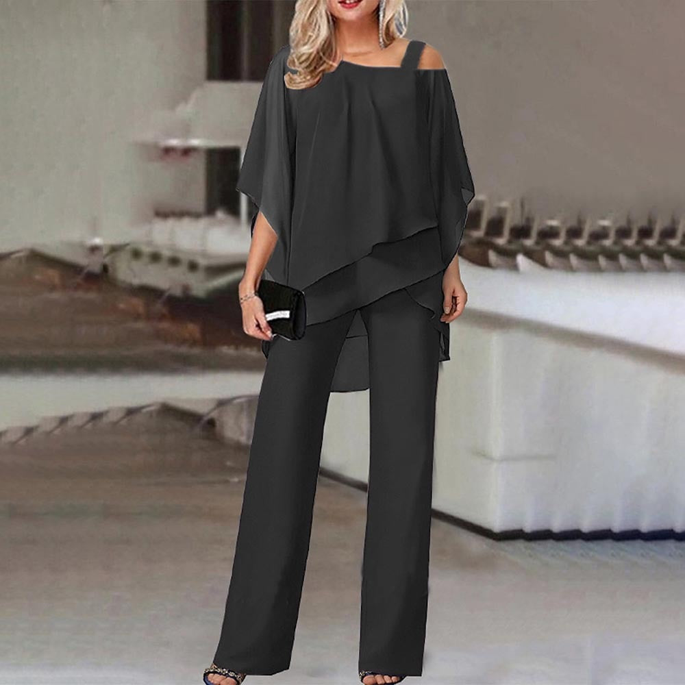 Donna in elegante tuta nera con spalle scoperte, accessoriata con pochette nera. Abbigliamento moda femminile, stile sofisticato e moderno.