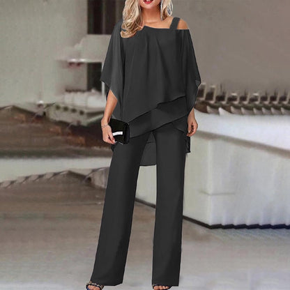 Donna in elegante tuta nera con spalle scoperte, accessoriata con pochette nera. Abbigliamento moda femminile, stile sofisticato e moderno.