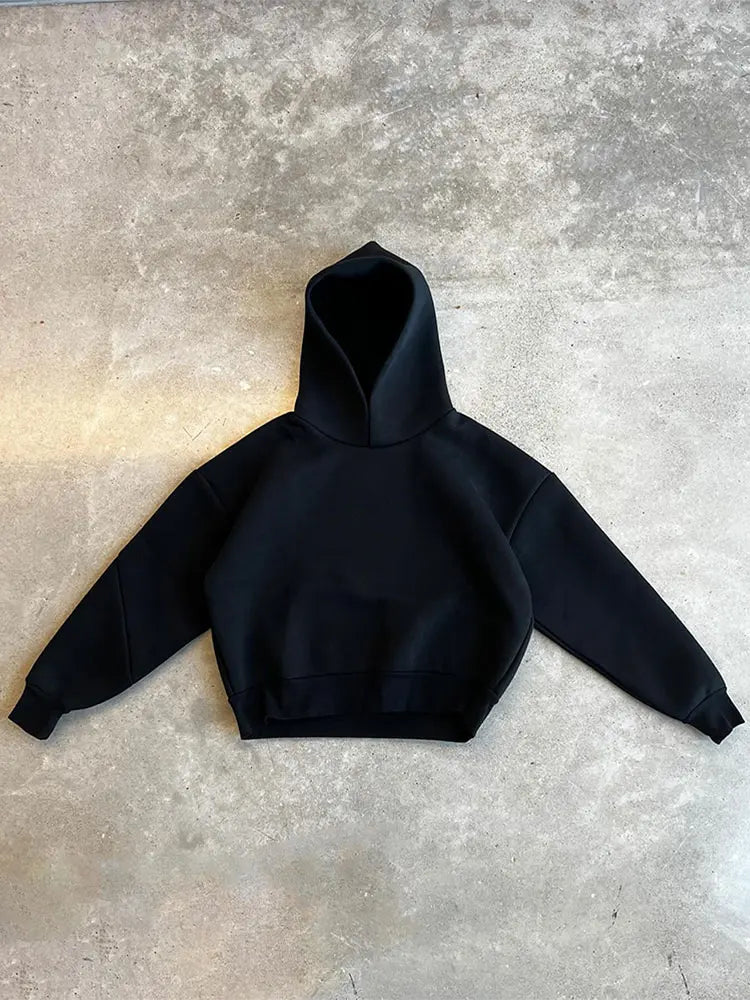 Felpa nera con cappuccio su sfondo grigio, design minimalista, moda casual, abbigliamento streetwear, tessuto morbido e confortevole.