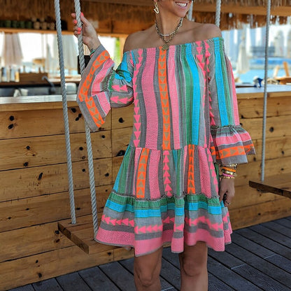 Donna con abito estivo colorato a righe e motivi geometrici, su altalena in legno. Moda estiva, abbigliamento casual, stile boho chic.