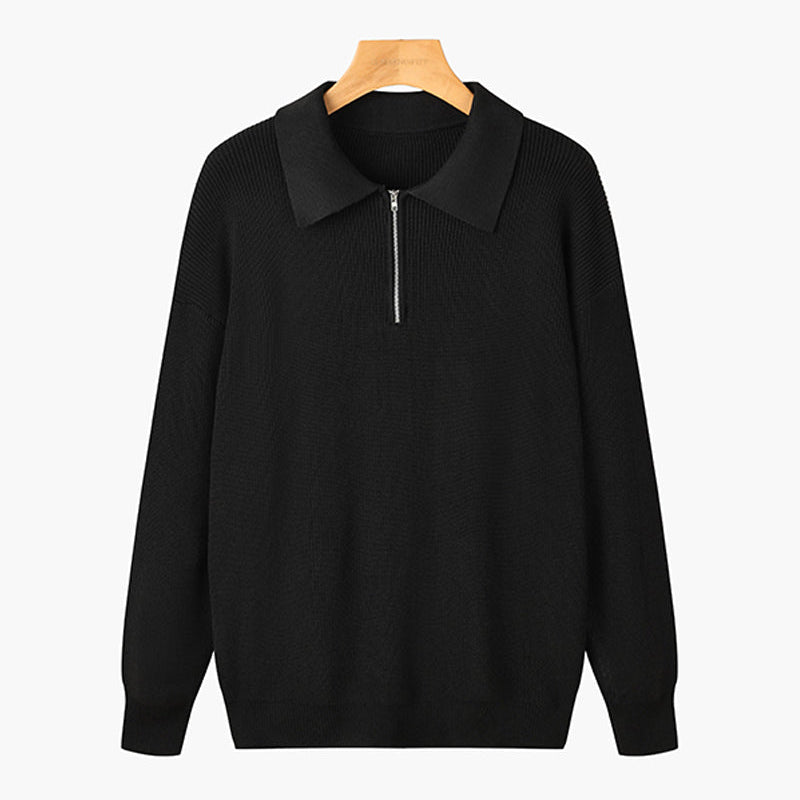 Maglione nero con zip frontale e colletto, appeso su gruccia di legno. Design elegante e versatile, ideale per moda autunnale e invernale.