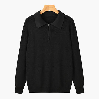 Maglione nero con zip frontale e colletto, appeso su gruccia di legno. Design elegante e versatile, ideale per moda autunnale e invernale.