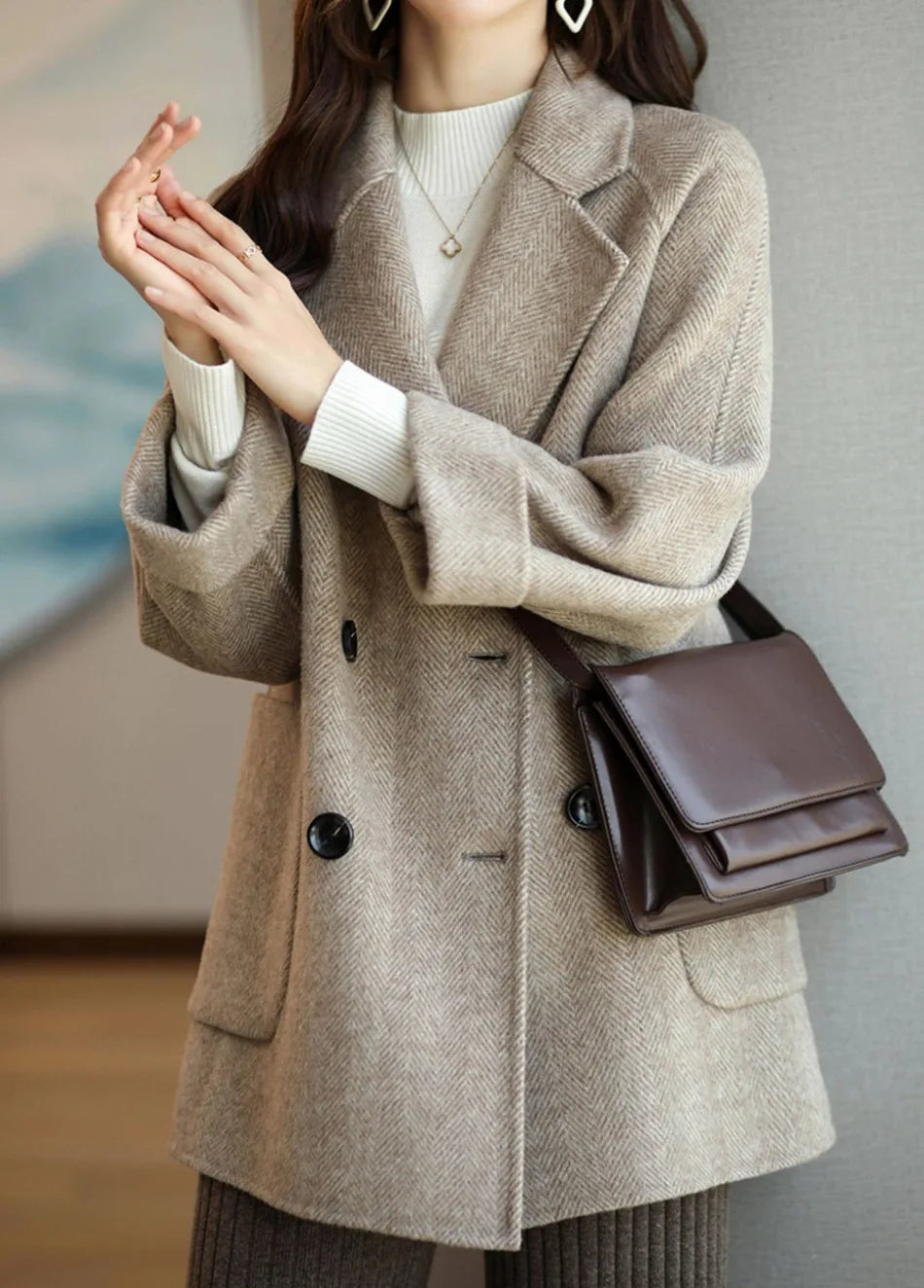 Cappotto beige elegante donna, doppio petto, abbinato a maglione bianco e borsa marrone. Moda autunno inverno, stile casual chic.