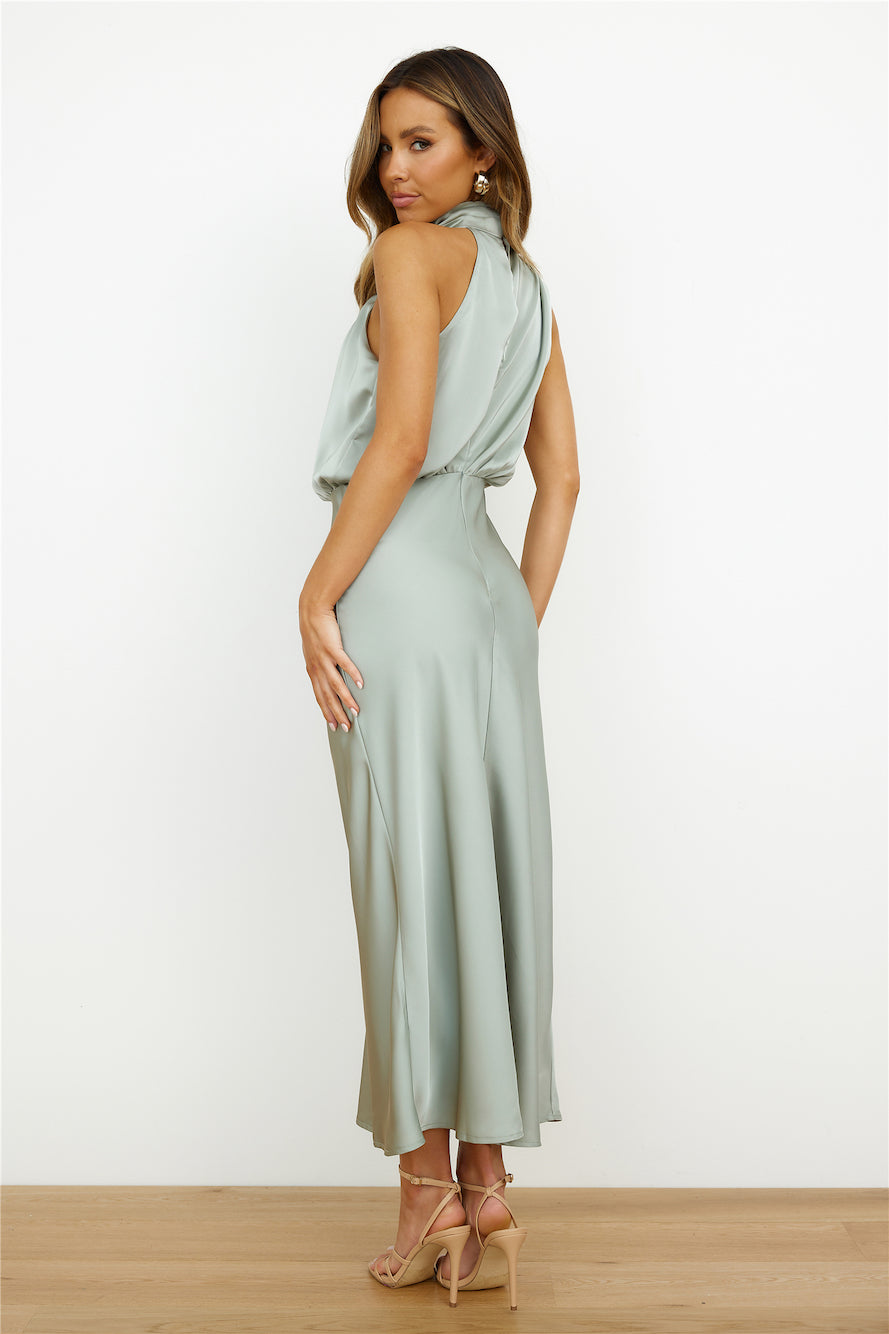 Donna in abito lungo verde salvia in raso, elegante e senza maniche, con sandali beige. Moda femminile, abbigliamento estivo chic.