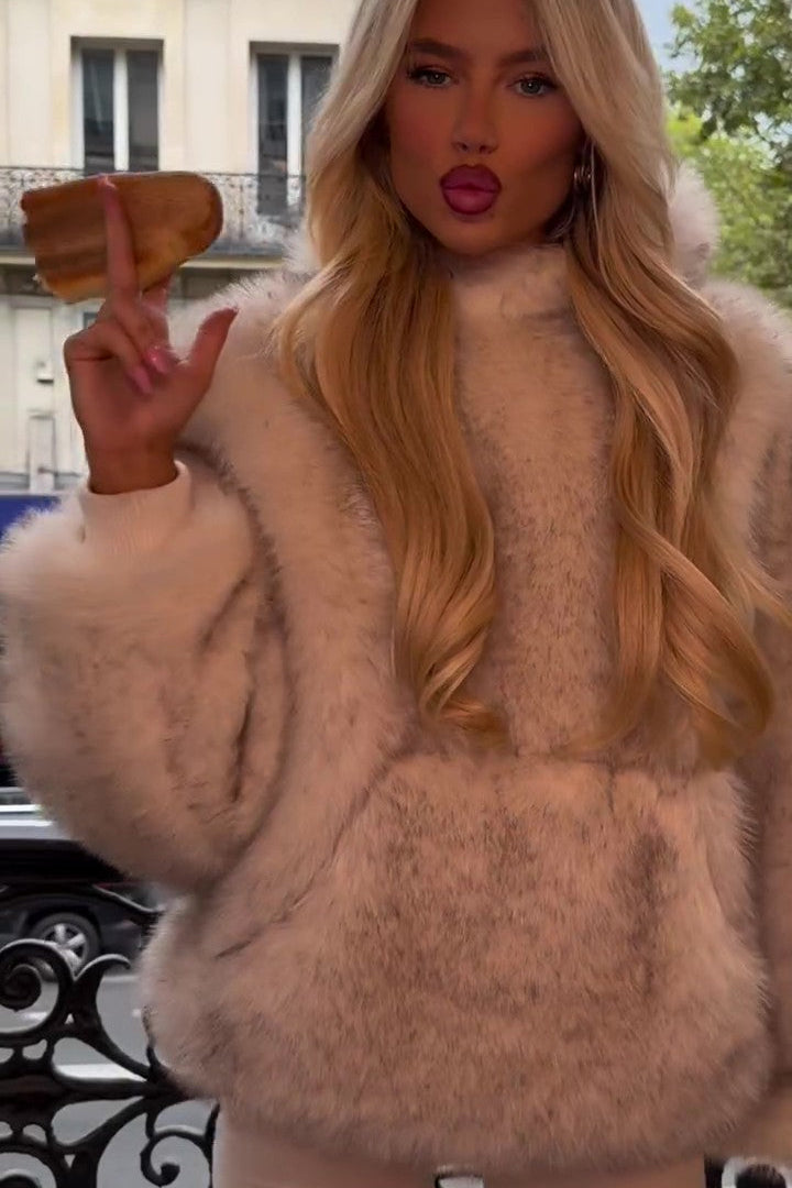 Bionda con cappotto di pelliccia beige, posa con espressione sicura su balcone parigino. Moda autunno inverno, stile elegante, lusso urbano.