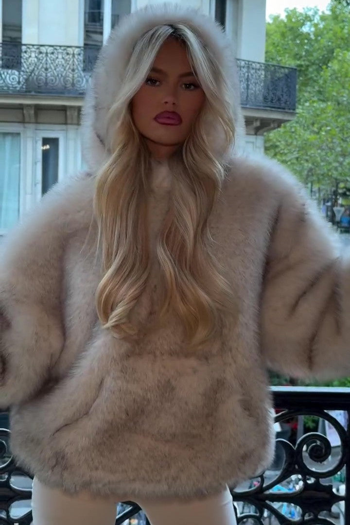 Donna con cappotto di pelliccia beige, capelli biondi lunghi, su balcone parigino. Moda autunnale, eleganza urbana, stile lussuoso.