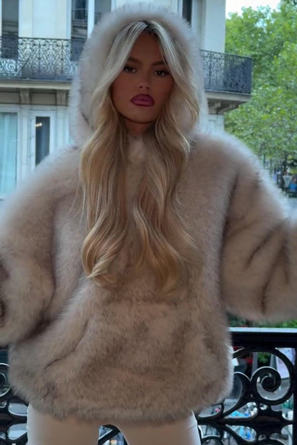 Donna con cappotto di pelliccia beige, capelli biondi lunghi, su balcone parigino. Moda autunnale, eleganza urbana, stile lussuoso.