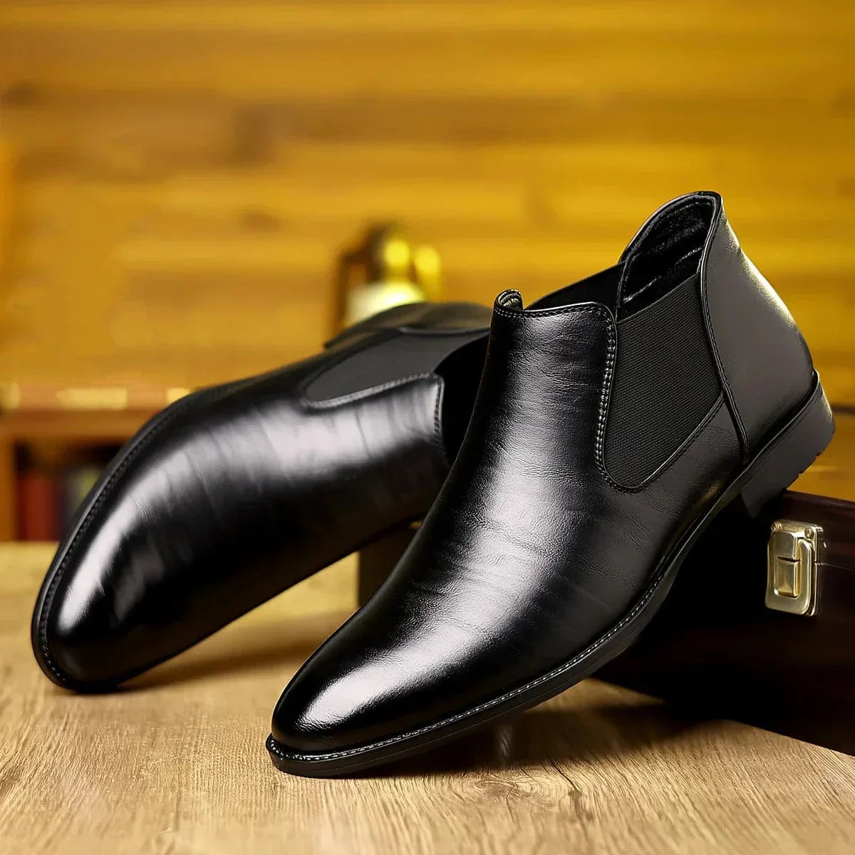 Scarpe eleganti da uomo in pelle nera, stile Chelsea, su sfondo di legno. Calzature formali, moda maschile, design classico e raffinato.