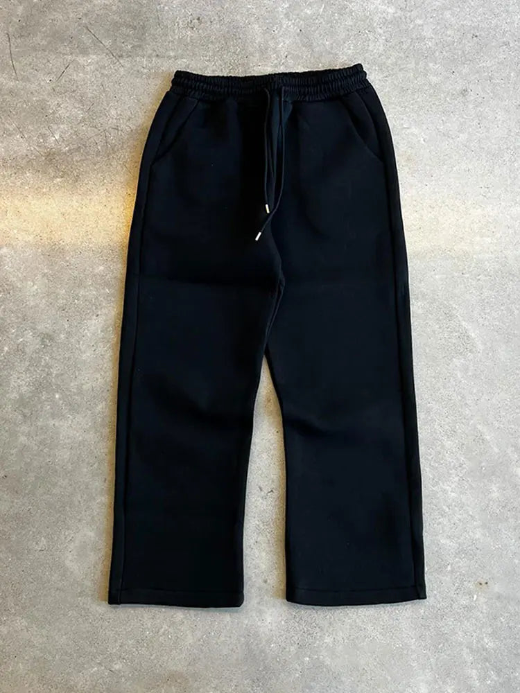 Pantaloni jogger neri su sfondo grigio, stile casual, con tasche laterali e coulisse in vita. Ideali per moda streetwear e abbigliamento comodo.