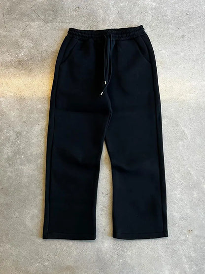 Pantaloni jogger neri su sfondo grigio, stile casual, con tasche laterali e coulisse in vita. Ideali per moda streetwear e abbigliamento comodo.