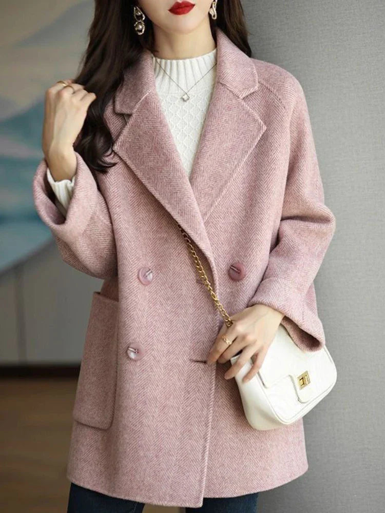 Donna con cappotto rosa elegante, doppio petto, indossa maglione bianco a collo alto. Borsa a tracolla bianca. Moda autunnale chic.