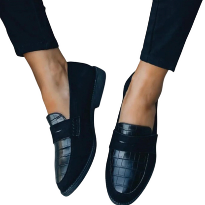 Scarpe mocassini donna nere eleganti, design in pelle lucida con motivo coccodrillo, indossate con pantaloni neri. Moda calzature femminili.