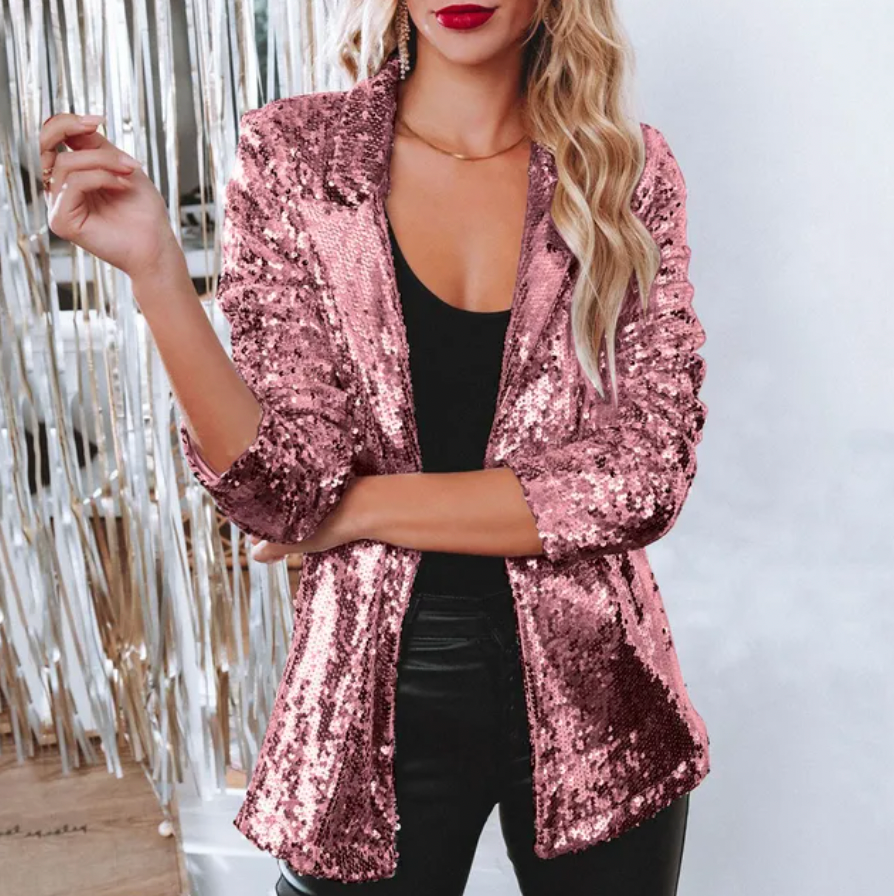 Giacca rosa con paillettes indossata da donna bionda, abbinata a top nero e pantaloni in pelle. Moda glamour, abbigliamento elegante per eventi serali.