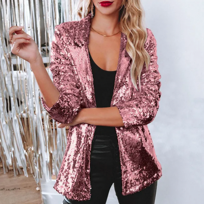 Giacca rosa con paillettes indossata da donna bionda, abbinata a top nero e pantaloni in pelle. Moda glamour, abbigliamento elegante per eventi serali.