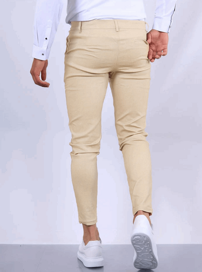 Pantaloni chino beige da uomo, vestibilità slim, abbinati a camicia bianca e scarpe da ginnastica bianche. Moda maschile casual elegante.
