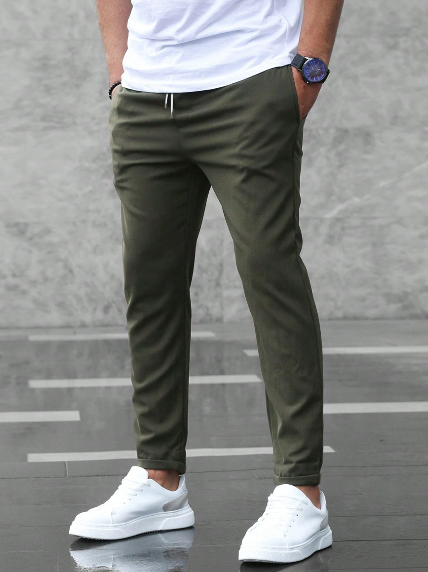 Pantaloni chino verde oliva da uomo, abbinati a scarpe da ginnastica bianche e maglietta bianca. Stile casual moderno, moda maschile.