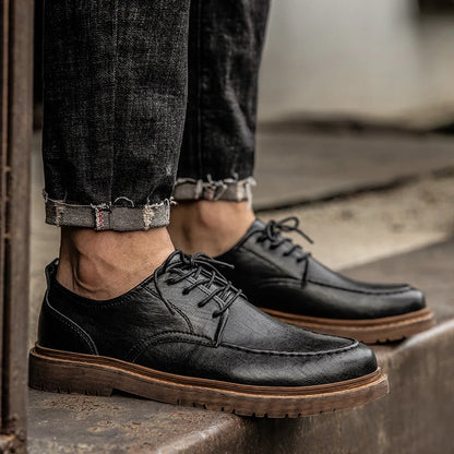 Scarpe eleganti in pelle nera da uomo, abbinate a jeans scuri. Calzature classiche con suola marrone, ideali per look casual e formali.