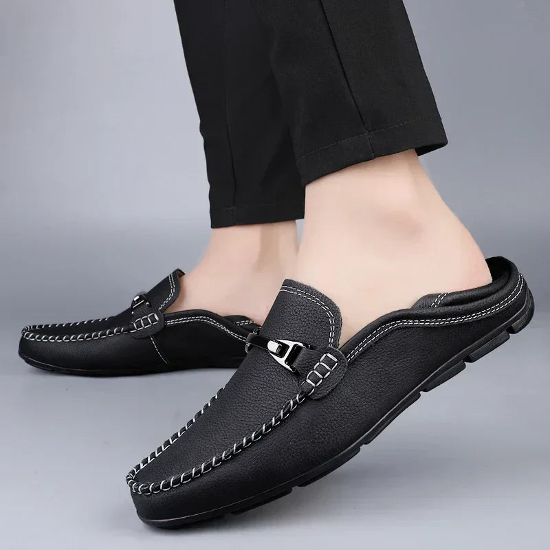 Scarpe mocassini da uomo in pelle nera, design elegante con cuciture bianche, indossate con pantaloni neri. Calzature casual e comode.