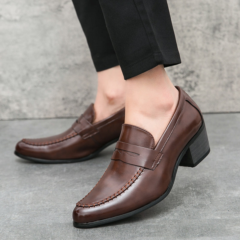 Scarpe eleganti uomo in pelle marrone, mocassini con tacco, indossate con pantaloni neri. Stile classico, moda maschile, calzature formali.