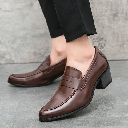 Scarpe eleganti uomo in pelle marrone, mocassini con tacco, indossate con pantaloni neri. Stile classico, moda maschile, calzature formali.