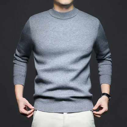 Maglione grigio uomo, maniche lunghe, collo alto, indossato su pantaloni chiari. Moda maschile elegante, abbigliamento casual autunnale.