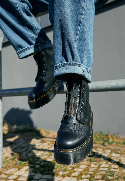 Jeans e stivali neri con suola spessa, stile casual urbano. Scarpe in pelle con lacci e zip, moda autunnale.