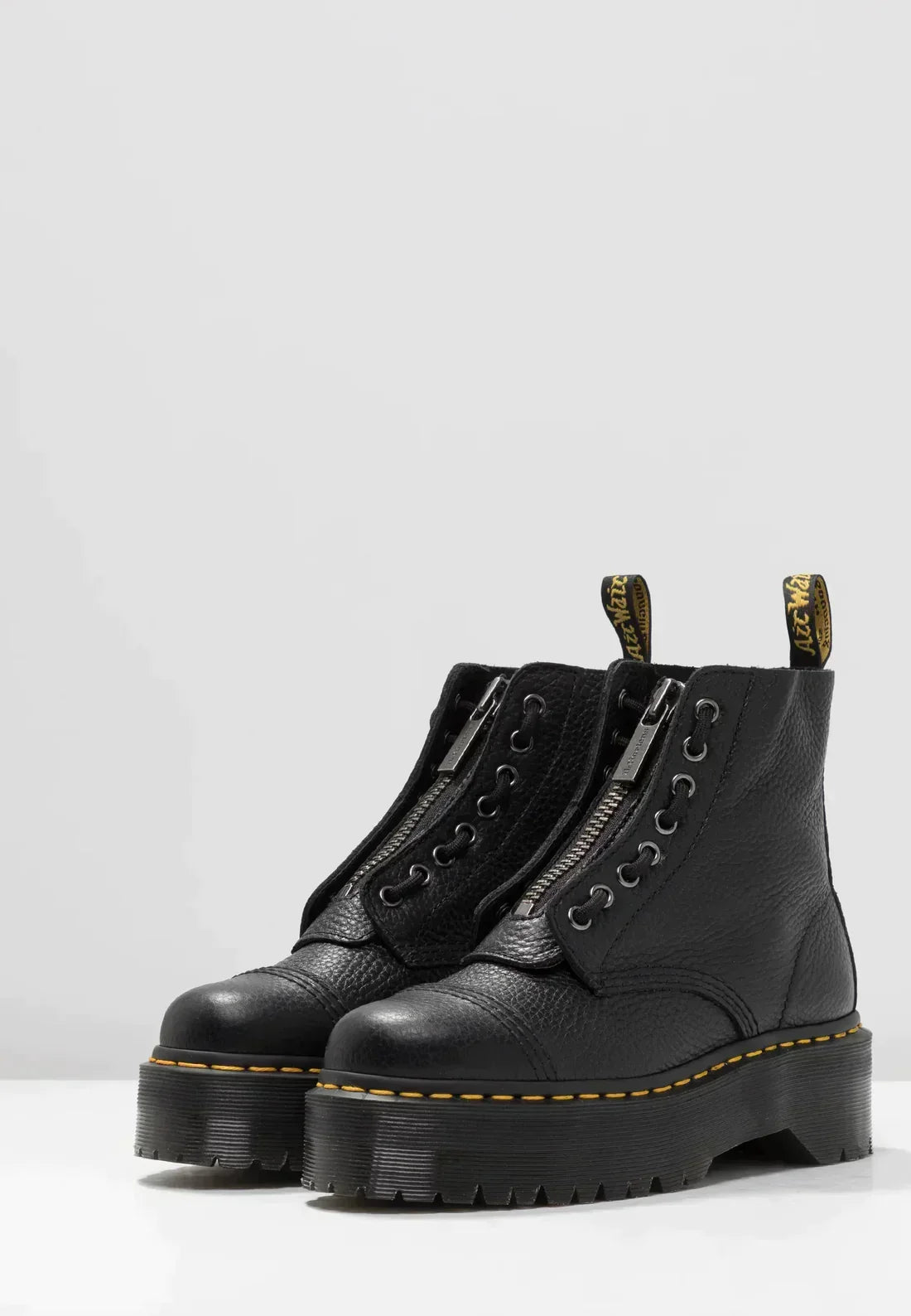 Stivali neri in pelle con suola spessa e cuciture gialle, chiusura con zip e lacci. Scarpe moda autunno inverno, stile punk rock.