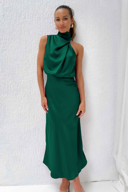 Donna in abito lungo verde elegante, design asimmetrico, posa su sfondo bianco. Moda femminile, abbigliamento da sera, stile sofisticato.