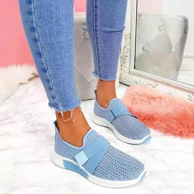 Scarpe da ginnastica blu in tessuto traspirante, indossate con jeans aderenti. Design moderno, suola bianca, perfette per look casual e sportivo.