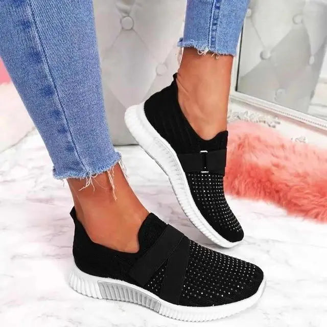 Scarpe da ginnastica nere con suola bianca, indossate con jeans strappati. Design moderno e traspirante, ideali per moda casual e comfort quotidiano.