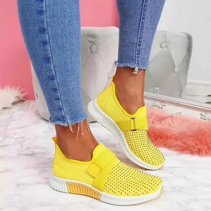 Scarpe da ginnastica gialle su pavimento in marmo, indossate con jeans aderenti. Design moderno, casual e alla moda. Scarpe sportive leggere.