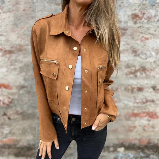 Giacca marrone da donna in pelle scamosciata con bottoni dorati, indossata sopra una maglietta bianca e jeans neri. Moda autunnale casual.