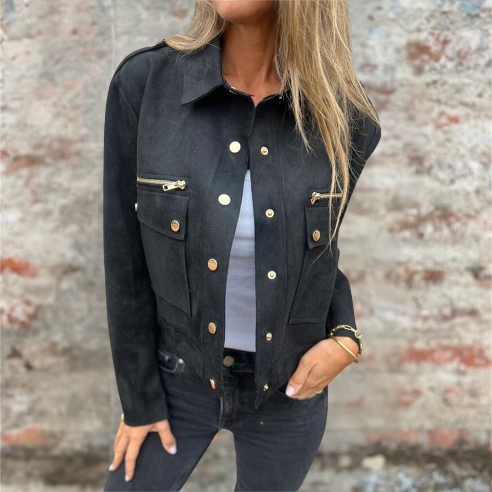Donna con giacca nera elegante, bottoni dorati, tasche con zip, sfondo muro rustico. Moda autunno, stile casual chic, abbigliamento femminile trendy.