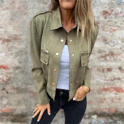 Donna con giacca verde militare, top bianco e jeans neri. Moda casual autunnale, stile urbano. Sfondo muro grigio.