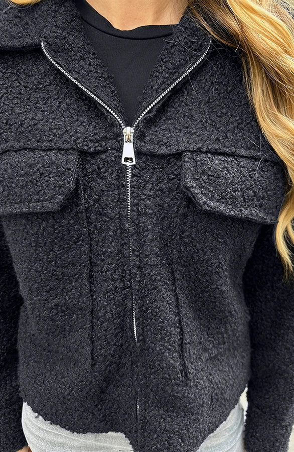 Giacca in pile nero con cerniera, tasche frontali, indossata da una persona. Tessuto morbido e caldo, ideale per l'inverno.