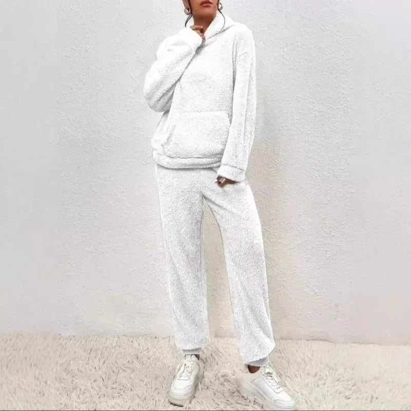 Donna in tuta bianca in pile, con cappuccio e tasca frontale, su sfondo bianco. Moda casual, abbigliamento comodo, stile invernale.