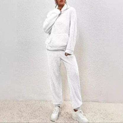 Donna in tuta bianca in pile, con cappuccio e tasca frontale, su sfondo bianco. Moda casual, abbigliamento comodo, stile invernale.